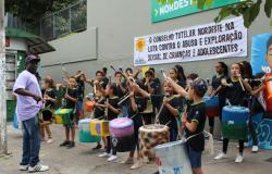 Mais de vinte crianças tocam instrumentos de percussão em evento de protesto contra a exploração sexual de crianças e adolescentes.