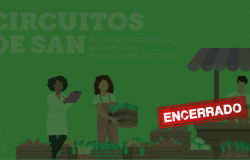 Uma mulher de jaleco anota em uma prancheta enquanto outra mulher organiza uma caixa de vegetais entre outros legumes e frutas exibidos. À esquerda, uma barraquinha com um homem atendendo. Acima e à direita, os dizeres "Circuitos de SAN". Abaixo e à esquerda, uma tarja vermelha escrito "encerrado". 