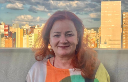 Diretora de Planejamento Estratégico e Inovação da SUMOB mulher com blusa de várias cores posa com prédios ao fundo