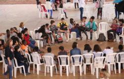 Grupo de adolescentes sentados em cadeiras brancas de plástico, em círculo, fazem uma roda de conversa na escola.