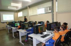 Instrutor do curso e crianças sentadas em frente ao computador