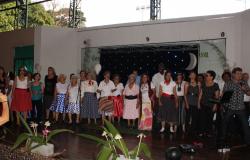 Cerca de vinte idosos caracterizados ao estilo da década de 1960, se apresentam no palco da homenagem ao Dia das Mães do Centro de Referência da Pessoa Idosa.