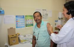 Cidadão recebe vacina de agente de saúde.
