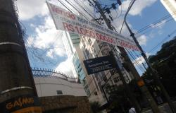 Placa informando Rua Gonçalves Dias 2180 a 2112, poste de energia á esquerda e faixa branca com dizeres de venda fixada de um poste a outro lado da rua 