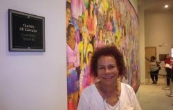 Dona Arlete sorri para foto em frente a quadro de obra de arte