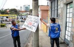 Dois agentes da prefeitura retiram faixa de propaganda irregular de poste em Belo Horizonte