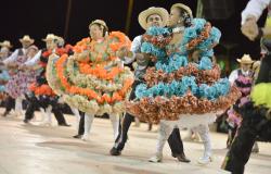 Pessoas usando vestidos coloridos e dançando festa junina.