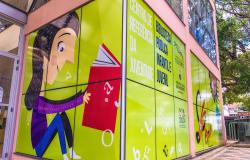 Detalhe da entrada da Biblioteca Pública Infantil e Juvenil de Belo Horizonte, no Centro de Referência da Juventude. No desenho colorido do viro, garota sorri e abre um livro.