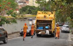 Três lixeiros acompanham o caminhão de lixo e recolhem material nas ruas de Belo Horizonte, durante o dia