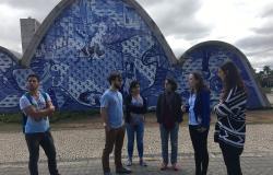 Grupo de cinco voluntários internacionais da PBH em frente ao painel de Portinari na Igreja de São Francisco, na Pampulha.