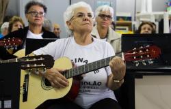 A idosa Maria Aparecida Linhares tocando violão