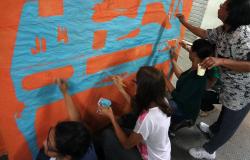 Quatro pessoas pintam mural na parede, atividade faz parte de oficina de artes da Escola Livre de Artes.