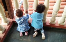 Duas crianças com menos de 2 anos na varanda de uma casa.