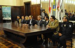 Autoridades municipais, militares e civis reunidos em mesa para concessão de entrevista coletiva