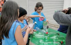 Três crianças fazem reciclagem com garrafas PET, uma das técnicas ensinadas nas oficinas de reaproveitamento da SLU.