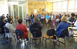 Quinze pessoas se reúnem em círculo, dinâmica do projeto Roda de Conversa que permite a troca de experiências.