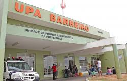 Fachada da UPA Barreiro, com viatura da Guarda Municipal e sete usuários, durante o dia.