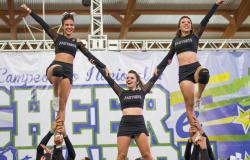 Grupo de cinco cheerleaders se apresenta, umas sobre as outras, formando uma pirâmide humana. 