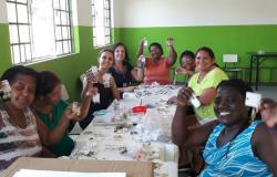 Grupo de mulheres em mesa mostrando bijuterias que fazem