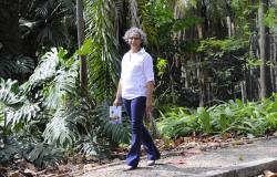 A escritora e servidora da Prefeitura, Soraia Evangelista, caminha pelo parque municipal segurando seu livro "Um câncer, uma felicidade..."