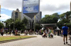 Mais de vinte pessoas interagem no cruzamento das avenidas Cristóvão Colombo e Getúlio Vargas; ao fundo, palco para apresentações e arranha-céu conhecido da Savassi e . 