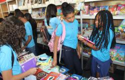 Crianças, alunas de escolas municipais, escolhem livros e lêem no Salão do Livro