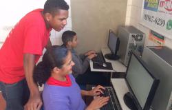 Monitor da Prodabel auxilia dois jovens em atividades de informática.