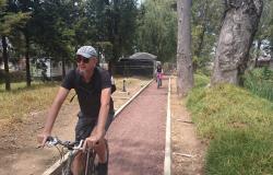 Homem anda de biclicleta em ciclovia em local arborizado. Ao fundo, outra pessoa de bicicleta.