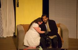 Casal se abraça sentado em sofá; cena do espetáculo "O Segredo de Susanna", da Cia Mineira de Ópera