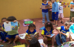 Dez crianças de idade entre 4 e 5 anos lendo livros infantis.
