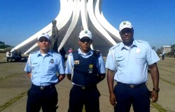 Três membros da Guarada Municipal à frente de igreja em Brasília. 