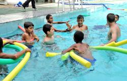 Oito meninos estão na piscina brincando com boias