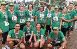 Cerca de treze usuários da Academia da Cidade da região Noroeste com camisetas verdes e crachás, participando de uma maratona de corrida.