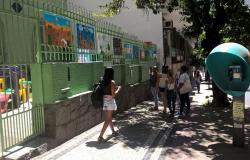 Dez telas pintadas por alunos em frente a E. M. Delfim Moreira; cerca de cinco passantes caminham pela calçada.
