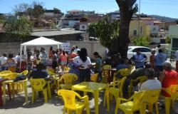 Mais de vinte pessoas se reúnem a céu aberto, com mesas e cadeiras e uma tenda informativa, próximo ao Centro de Saúde Capitão Eduardo. Imagem ilustrativa