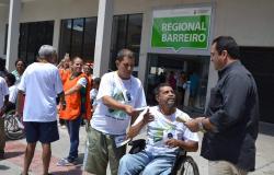 Cadeirante interage com dois homem na frente do Centro Dia Barreiro. 
