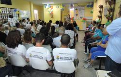 Mais de vinte profissionais do Centro de Saúde Padre Joaquim Maia, na Pampulha, reunidos na sala de espera do local, que comemora seu 10º aniversário; balões e adereços enfeitam o local. 