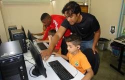 Dois técnicos da Prodabel ensinam duas crianças da Rede Municipal de Educação da PBH a acessar e utilizar computadores. 