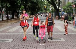 Dois homens, uma mulher e duas crianças caminham com um carrinho de bebê na Savassi. 