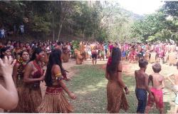 Mais de vinte índios da tribo Pataxó fazem círculo, junto a alunos de escola municipal.