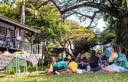 Cerca de sete crianças e um adulto fazem piquenique no gramado do Museu Histórico Abílio Barreto; ao fundo, casarão do museu.