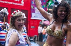 Duas mulheres sorriem com adereços de carnaval. 