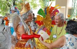 Duas idosas com fantasias de carnaval brincam com duas idosas com roupas comuns.