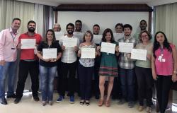 Treze servidores, com certificados em mãos, posam para foto ao lado de um dos professores.