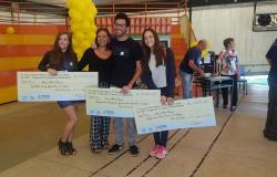 Quatro vencedores de concurso de vídeo "O Trânsito e o Valor da Vida", promovido pela BHTrans, exibem três cheques grandes.