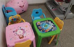 Quatro cadeiras e cuas mesas infantis e um baú em forma de porquinho fazem parte do Cantinho da Criança, que estimula a leitura infantil.
