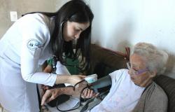 Médica afere pressão de paciente idosa em atendimento domiciliar. 