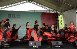 Nove mulheres vestidas de preto e vermelho fazem apresentação de dança cigana em palco. 