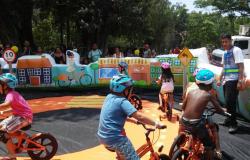 Quatro crianças em biciletas, auxiliadas por monitor, em Escolinha de Bike circuito didático de trânsito, na Fundação de Parques Municipais.