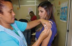 Técnica de saúde vacina braço de mulher contra a Influenza.